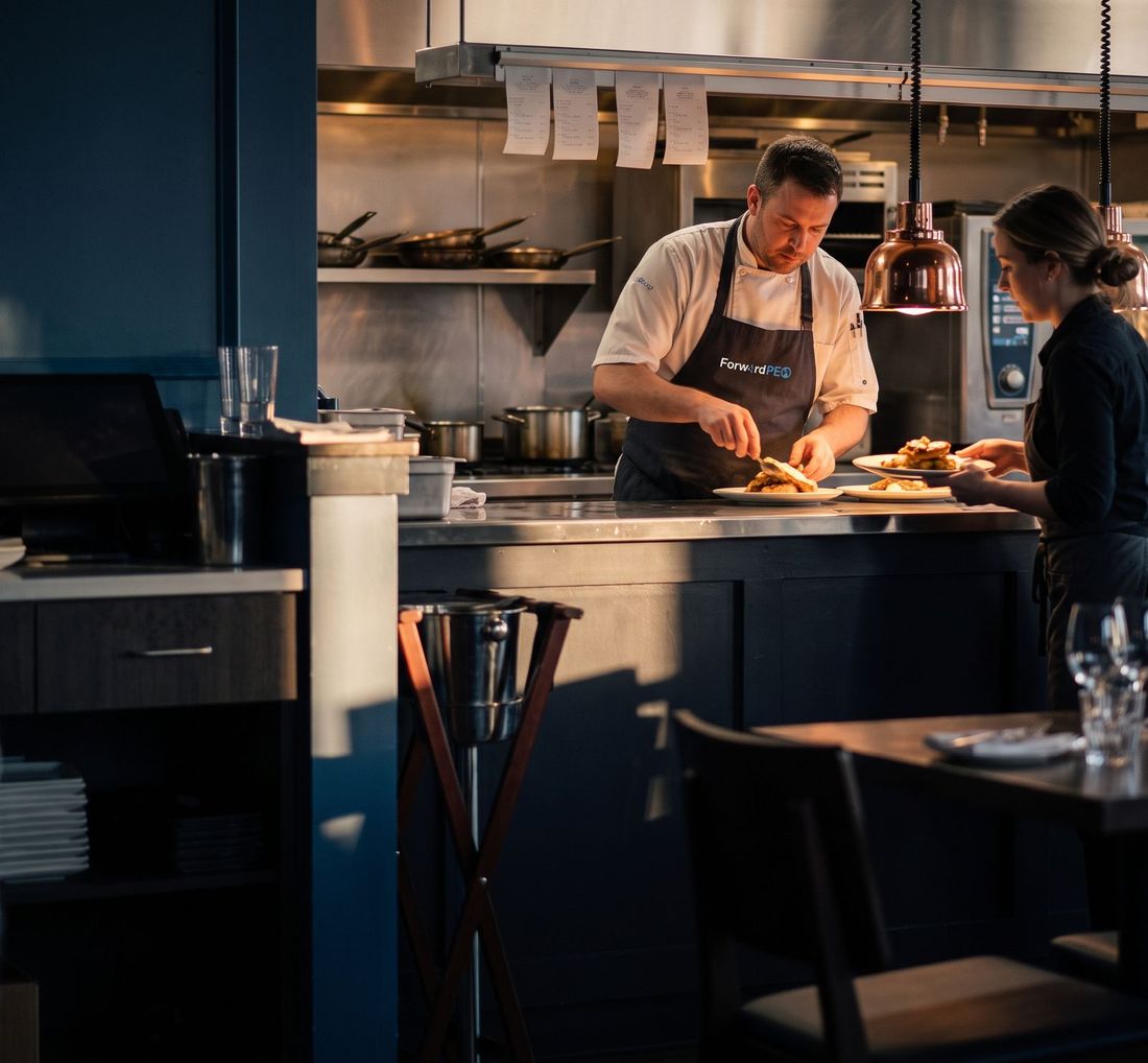 Chef and server preparing plates in a restaurant kitchen